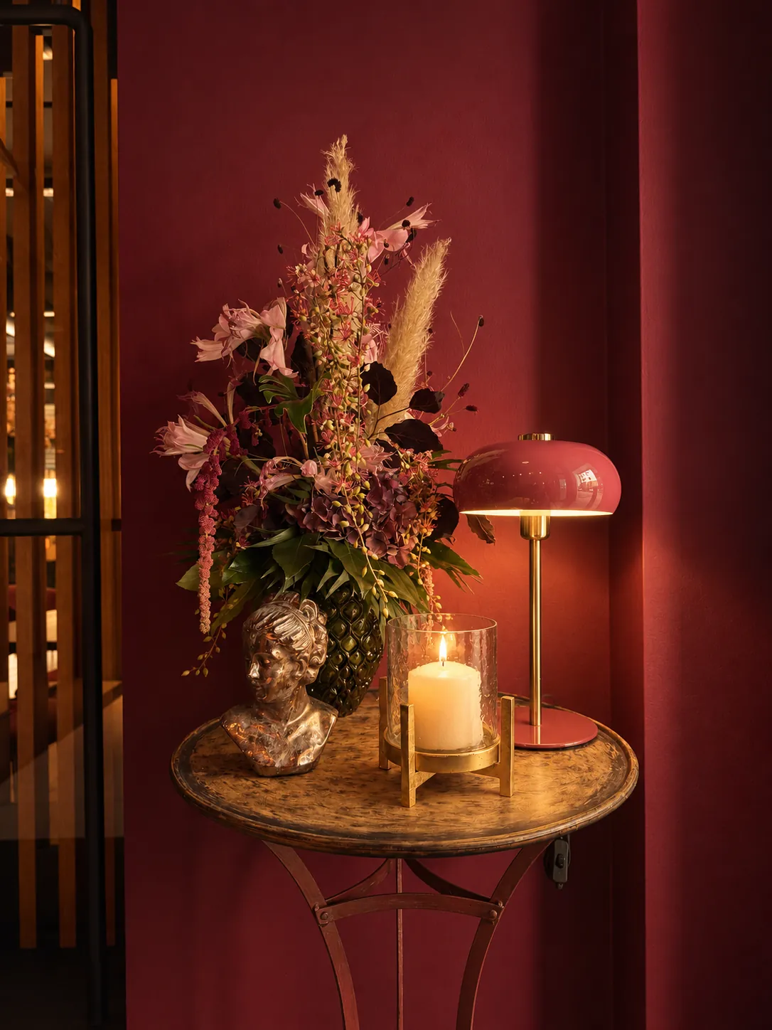 Bouquet, bougie et lampe sur une console, mur bordeaux de la brasserie Poline